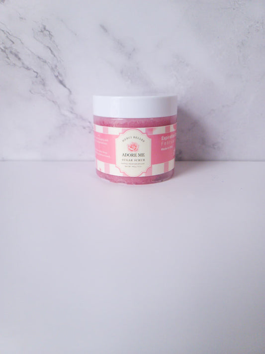 Pink sugar scrub in a jar with white cover and label.
Text: Merci Belles Sugar Scrub. Handmade with Love. 6oz.